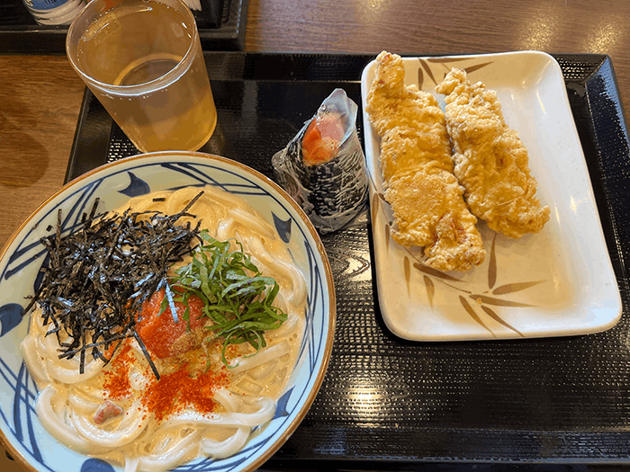 明太クリームうどんの画像。かしわ天と明太子おにぎりも写っている。